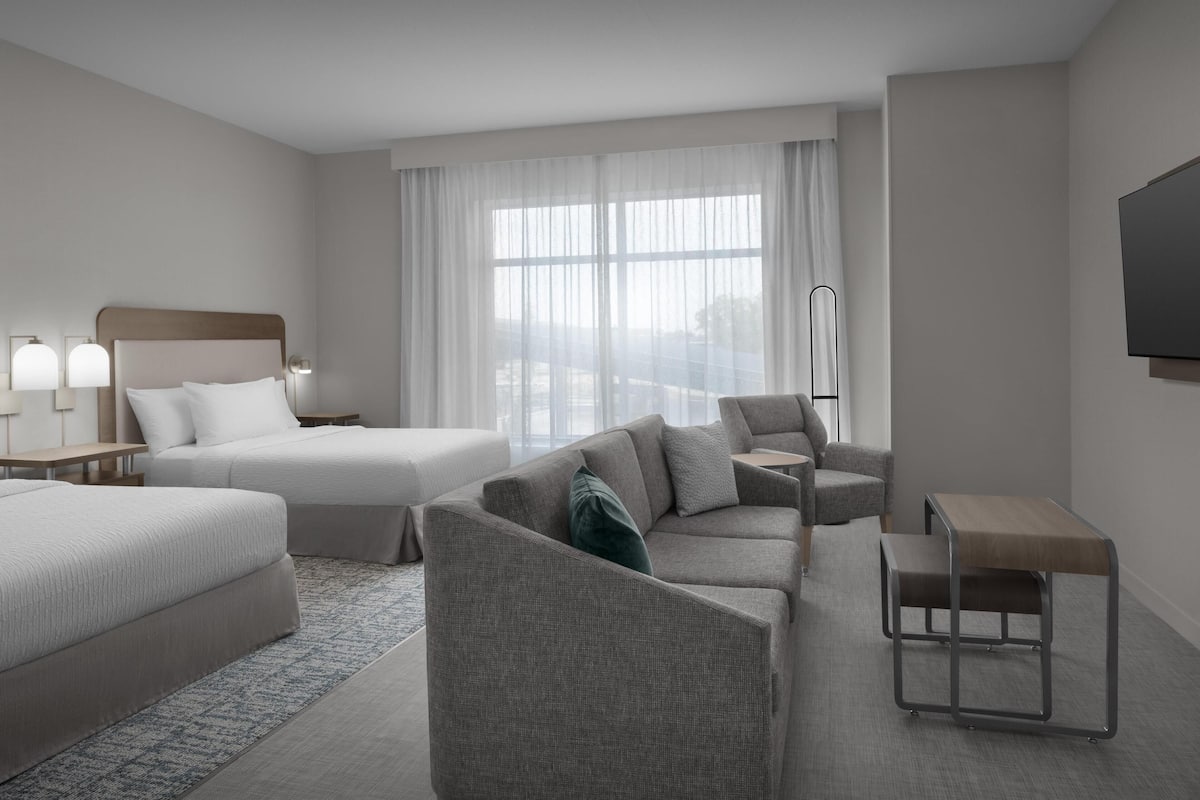 Une chambre d’hôtel avec un lit, un canapé, un bureau et une télévision.