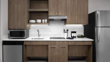 A modern kitchen with wooden cabinets, a stainless steel refrigerator, a microwave, and a dishwasher.