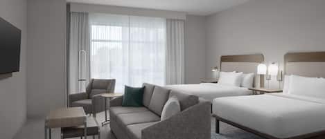 Habitación de hotel con sofá, una mesita, cama y televisor montado en la pared.