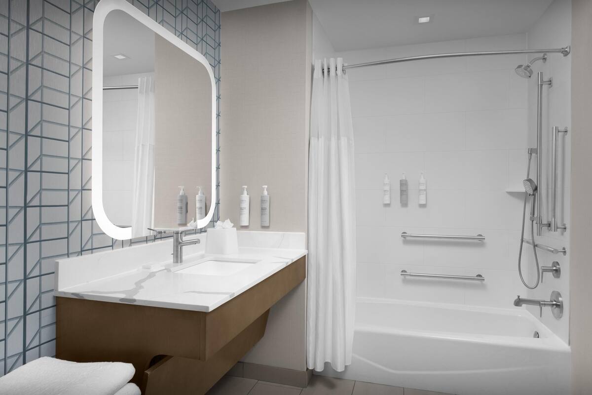 Une salle de bain moderne avec un grand miroir, deux lavabos, une baignoire et une douche.