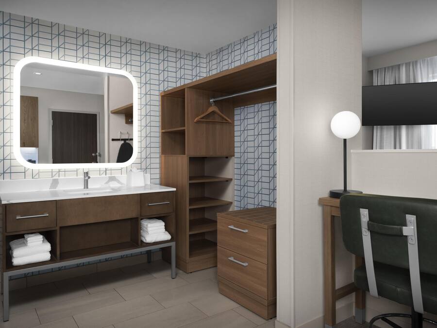 A modern bathroom with a large mirror, wooden vanity, and a walk-in closet.