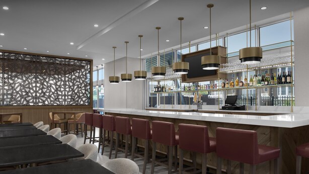 A modern bar area with a long counter, multiple bar stools, and a decorative wall with geometric patterns. - Tru By Hilton Columbia Downtown (Columbia)