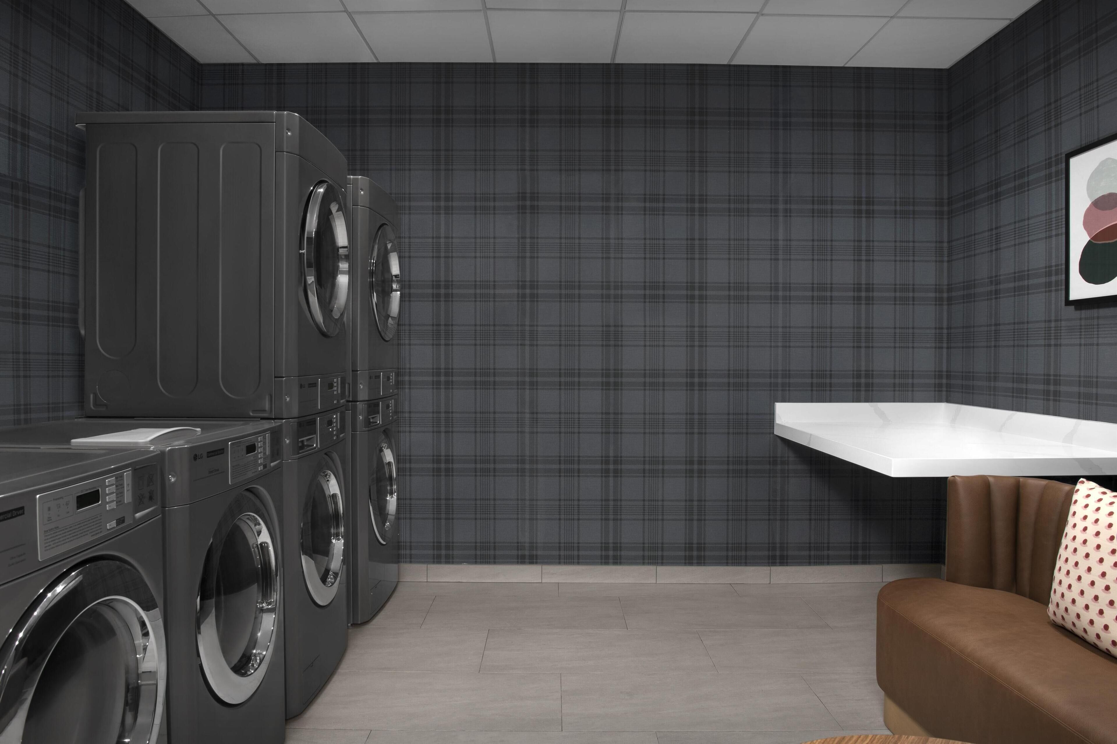 A laundry room with a washing machine, dryer, and a white shelf.