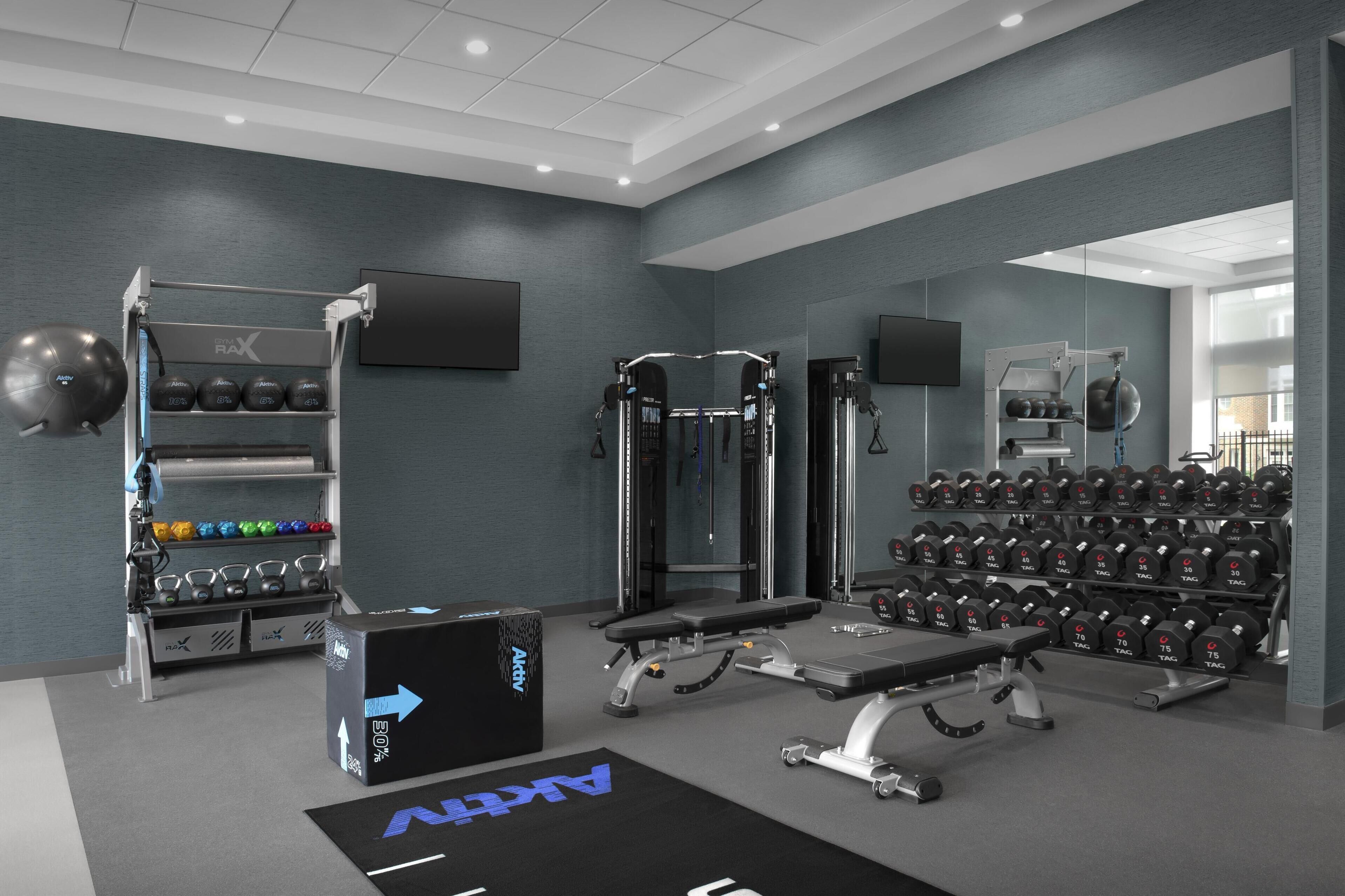 A modern gym with weightlifting equipment, a bench, and a mirrored wall.