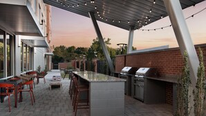 An outdoor patio with a bar area, seating, and a grill station. - Tru By Hilton Columbia Downtown (Columbia)