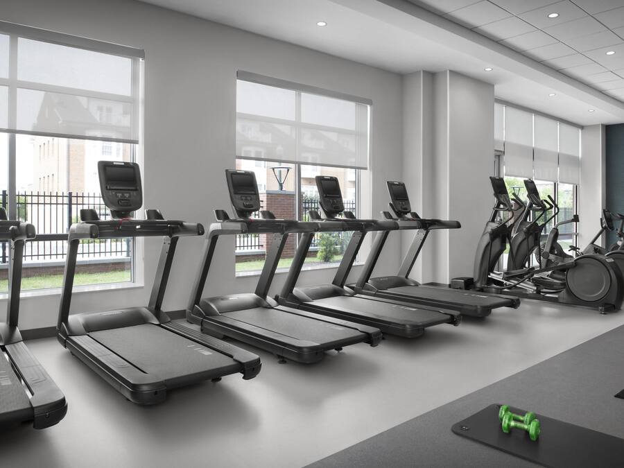 A gym with treadmills, a weight bench, and dumbbells.