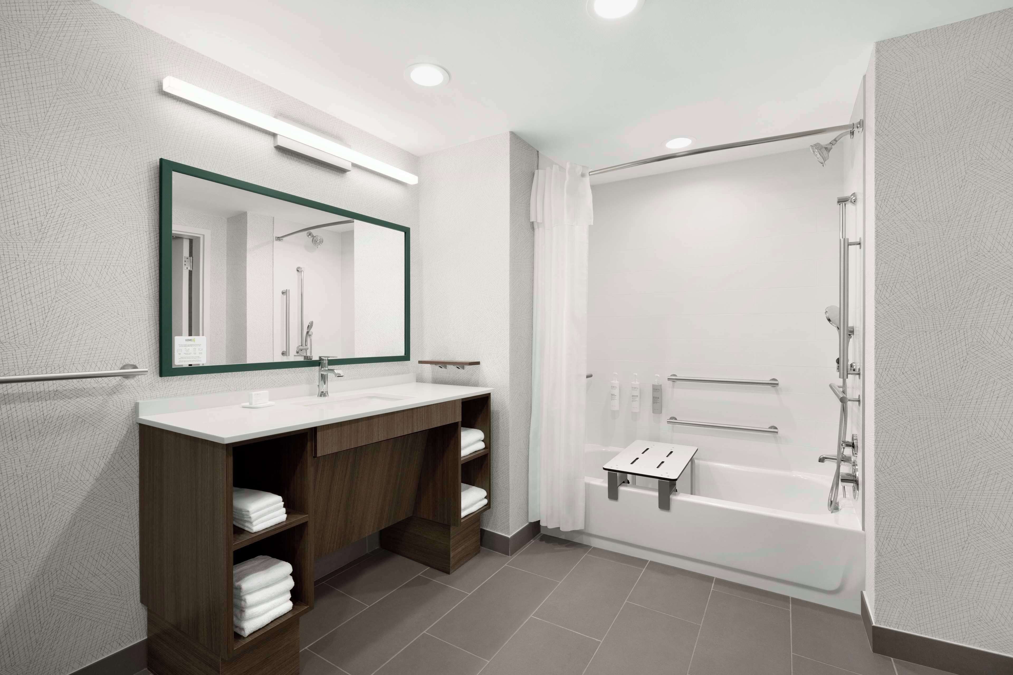 A modern bathroom with a large mirror, dual sinks, a shower, and a bathtub.
