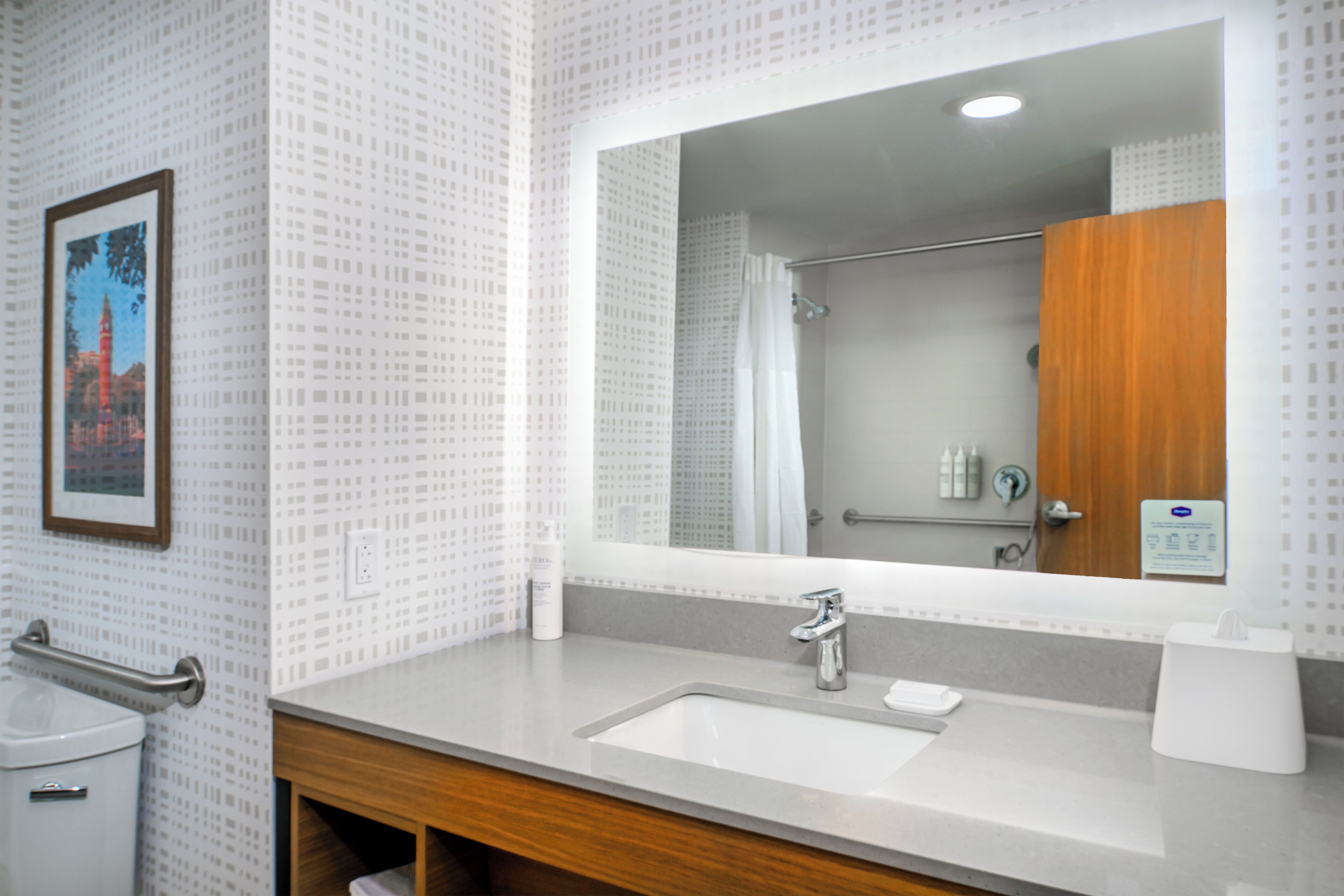 A bathroom with a sink, mirror, and shower.