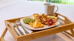 A breakfast tray with toast, fruit, and a mug on a wooden table in a hotel room. - Eclectic Bungalow close to Volcanoes National Park (Volcano)