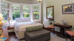 A bedroom with a bed, bedside tables, a desk, and a chair. - Comfortable Room in Historic Bed and Breakfast (Volcano)