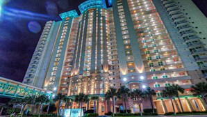 A high-rise hotel with multiple floors, balconies, and a well-lit entrance. - AQUA 1509 — Luxury Oceanfront Condo• 3 BD• Steps to Pier Park (Panama City Beach)
