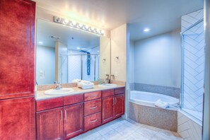 Une salle de bain avec deux lavabos, un grand miroir et une baignoire.