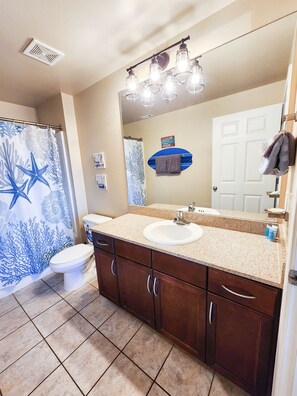 A bathroom with a double sink vanity, a shower curtain with a sea life design, a toilet, and a mirror with lights above the sink. - Next to 10th Floor Pool, incredible views! Light Show From Balcony! (Panama City Beach)