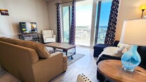 A modern living room with a sofa, armchair, and a round table with a lamp. - Next to 10th Floor Pool, incredible views! Light Show From Balcony! (Panama City Beach)