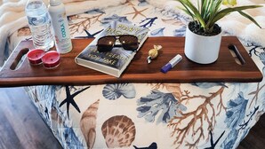 A bed with a floral bedspread, a tray with a book, a plant, and a water bottle. - Gorgeous Set up! Dive into the best vacation with Best Amenities! (Panama City Beach)