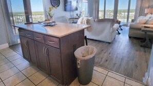 Amplia zona de estar con isla de cocina, ventanas grandes y ventilador de techo.