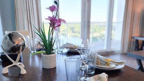 Una mesa de comedor dispuesta con platos, vasos, una esfera de cristal y una orquídea en maceta.