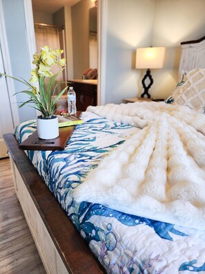 A bed with a floral bedspread, a bedside table with a plant and a water bottle, and a nightstand with a lamp. - Immaculate! Large and inviting! Dive into the best vacation NOW! (Panama City Beach)