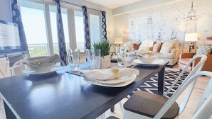 A modern dining area with a dark wooden table, white chairs, and a ceiling fan. - Immaculate! Large and inviting! Dive into the best vacation NOW! (Panama City Beach)