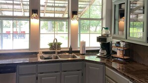 A kitchen with a large window, a sink, and a coffee maker.