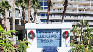 A hotel entrance with a circular pathway leading to a bench, surrounded by palm trees and greenery. - Best Location, 3rd floor condo! Enjoy the incredible views and privacy! (Panama City Beach)