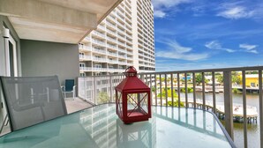A balcony with a glass table, a red lantern, and a view of a high-rise building and water. - Best Location, 3rd floor condo! Enjoy the incredible views and privacy! (Panama City Beach)