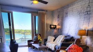 A modern living room with a view of a lake, a ceiling fan, and a brick wall.