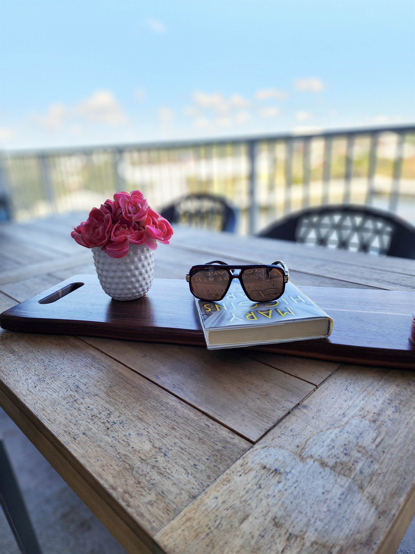 A wooden table with a book and a pair of sunglasses on it.