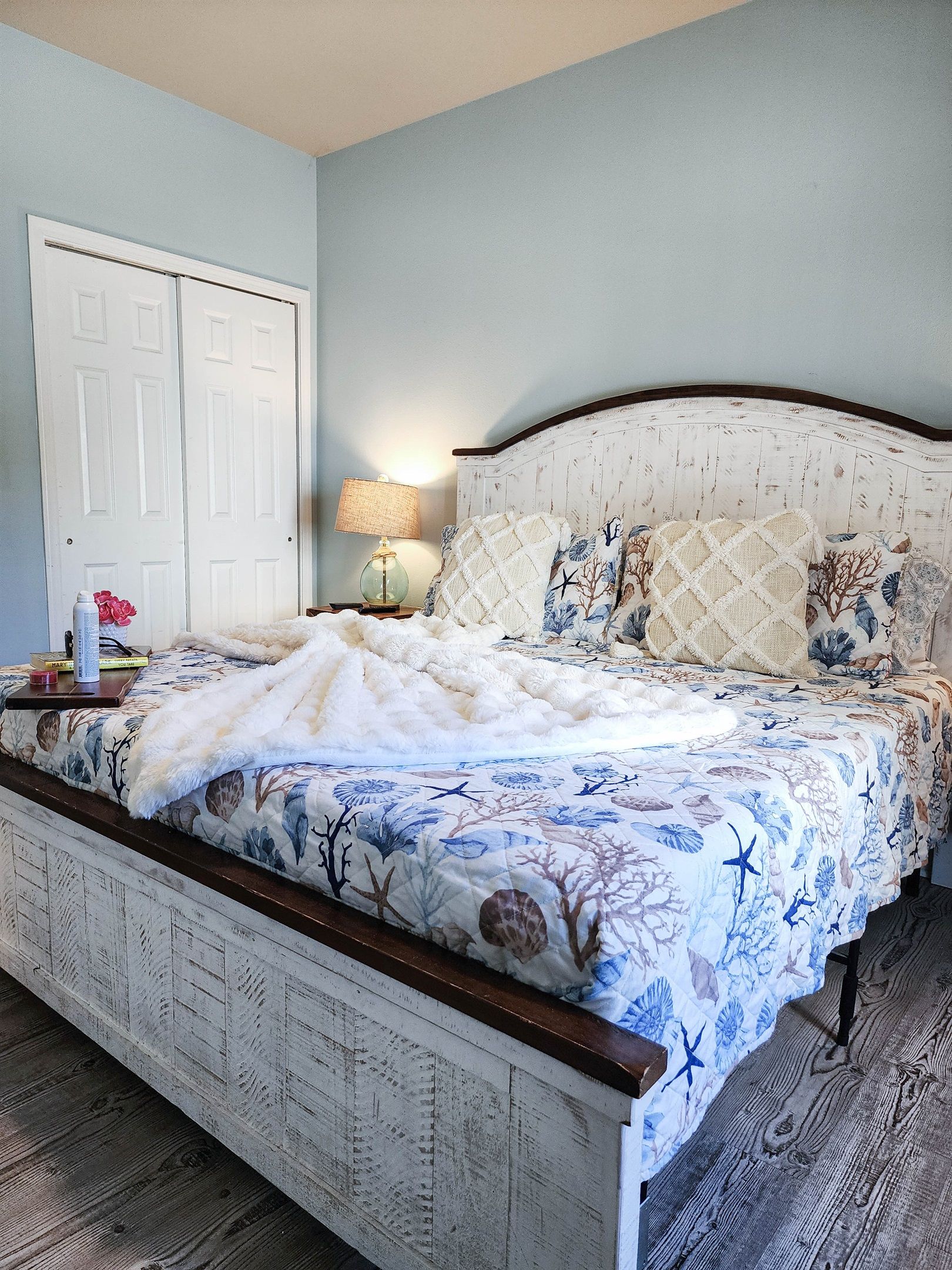 Un dormitorio con cama, mesita de noche, lámpara y una puerta.