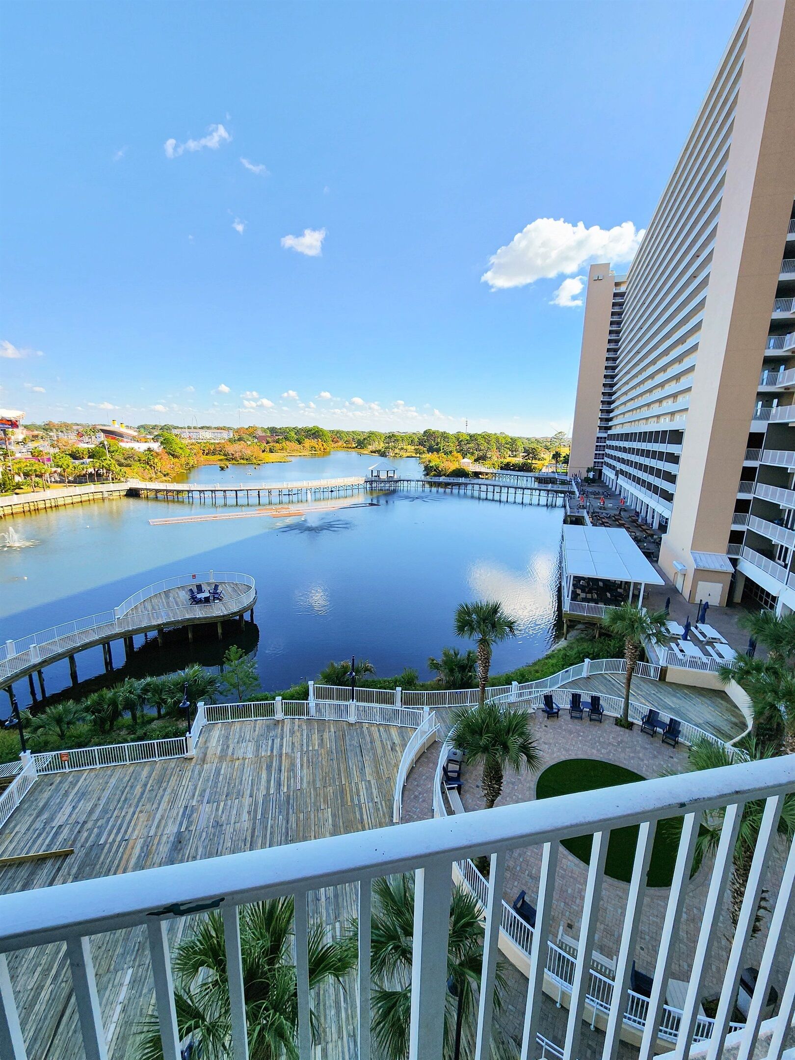 Un hotel de gran altura con vista a un lago tranquilo, una terraza de madera y un puente.