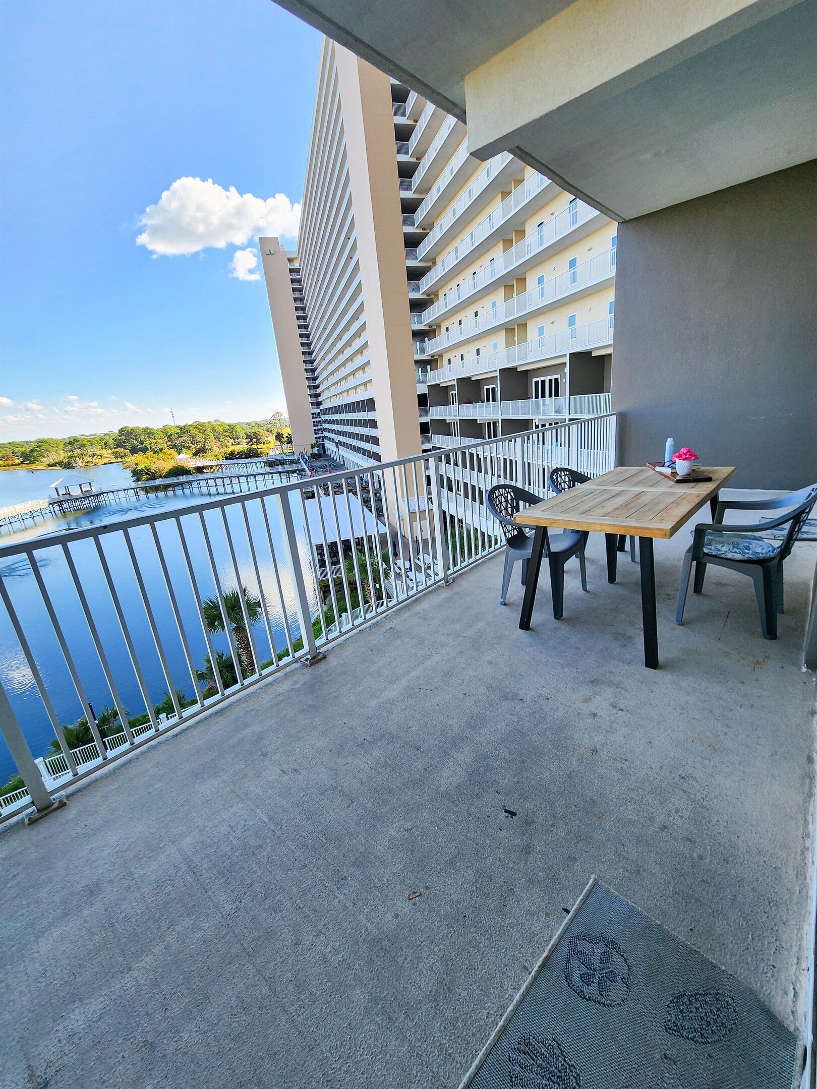 Un balcon donnant sur une étendue d’eau, un immeuble doté de plusieurs balcons et une table avec des chaises.