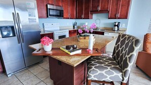 A modern kitchen with wooden cabinets, stainless steel appliances, and a central island with seating. - Perfect location on 5 FTH FLOOR! Amazing set up for a memorable stay! (Panama City Beach)