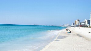 A beach with a clear blue sky, a sandy shore, and a pier extending into the water. - Super Convenient 5th FLOOR- 537 !  LOCATION, AMENITIES, And Amazing Views! (Panama City Beach)