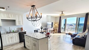 A spacious living area with a large island, a dining area, and a balcony with a view. - Exceptional unit 633!Accessible and  Inviting! Perfect Beach set up! (Panama City Beach)