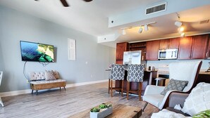 A modern living room with a wooden coffee table, a sofa, and a dining area with a kitchen in the background. - Light Fountain Show View, Laketown  735, Spectacular Unit And Amenities (Panama City Beach)