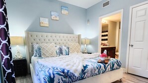 A bedroom with a large bed, a ceiling fan, and a door leading to a bathroom. - Light Fountain Show View, Laketown  735, Spectacular Unit And Amenities (Panama City Beach)
