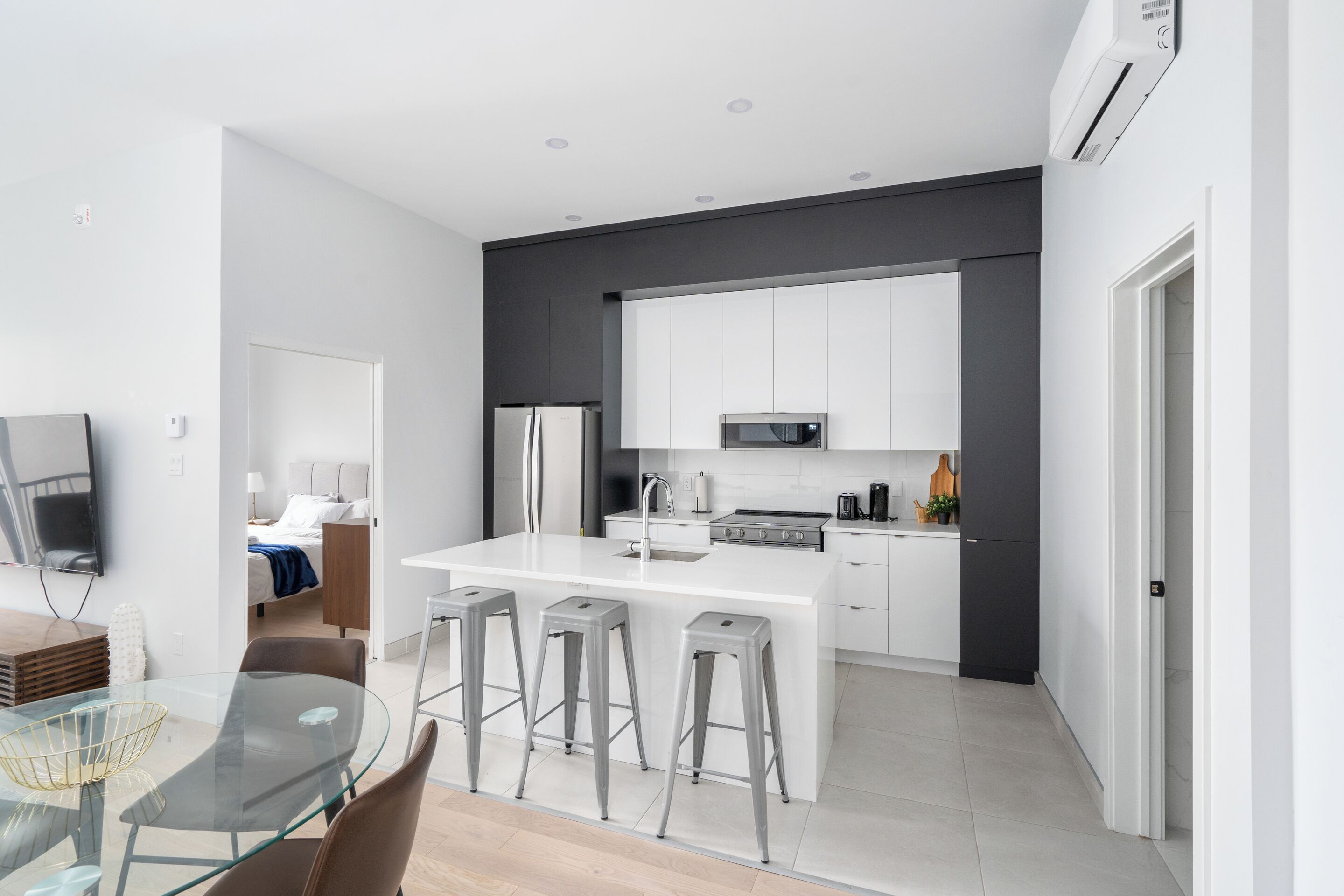 A modern kitchen with white cabinets, stainless steel appliances, and a central island with bar stools.
