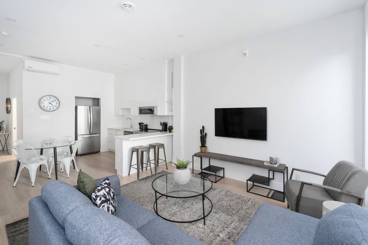A modern living room with a grey sofa, a coffee table, and a TV mounted on the wall.