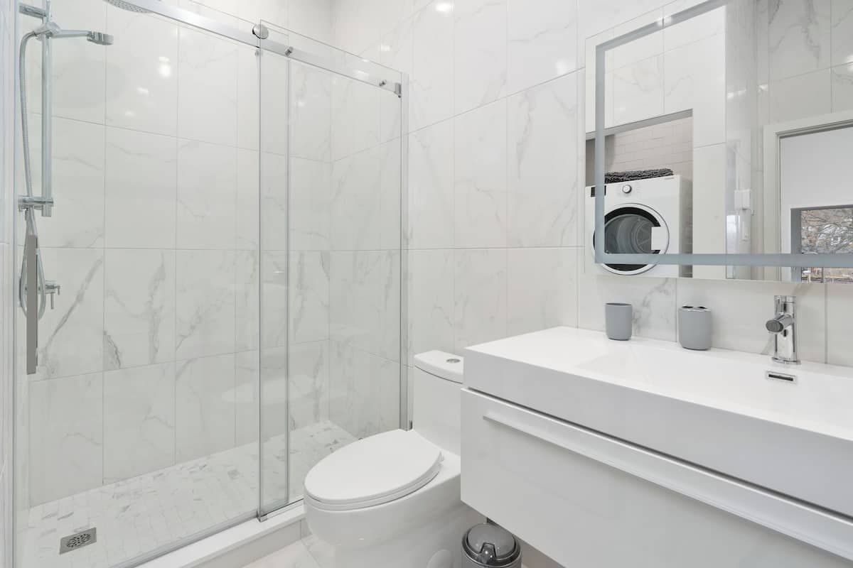 A modern bathroom with a glass shower enclosure, a white toilet, and a vanity with a mirror.