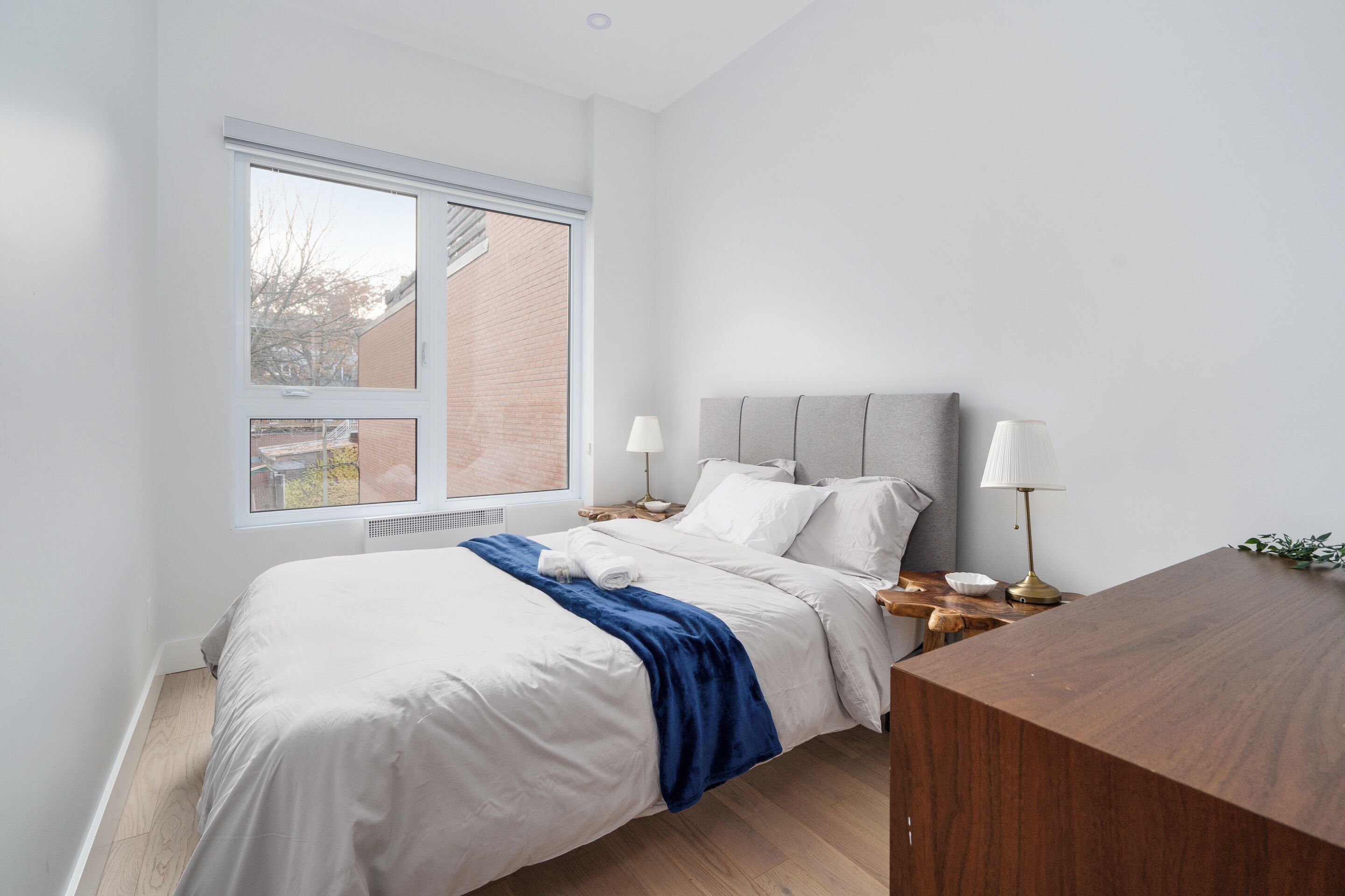Une chambre à coucher comprenant un lit, deux tables de chevet, une commode, une fenêtre et un bureau en bois.
