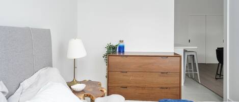 Une chambre moderne avec un lit, une table de chevet, une lampe, une commode et une vue sur la salle de bain adjacente.