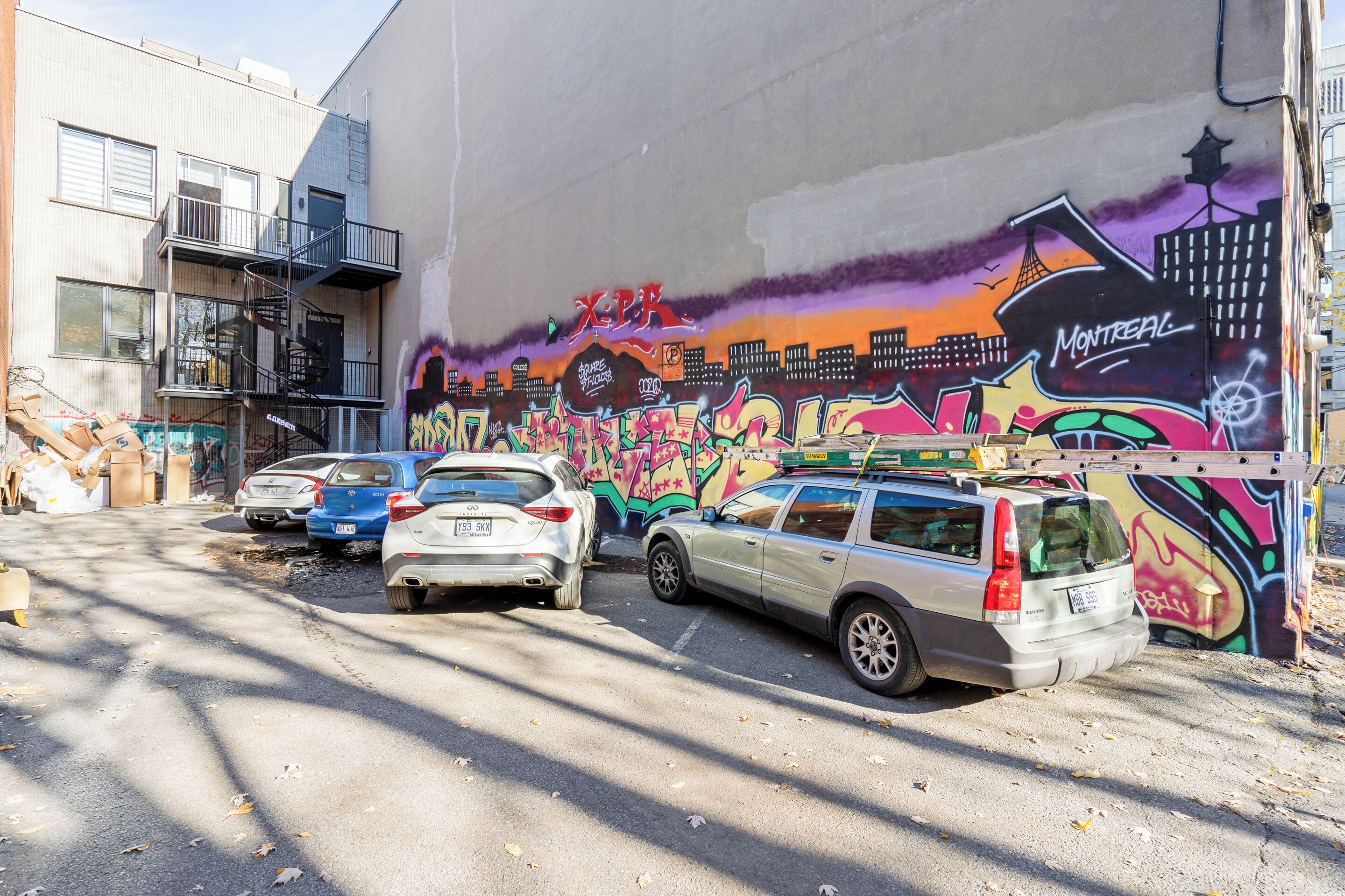 Un estacionamiento con autos y un mural grande en un edificio.