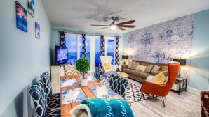 Una sala de estar moderna con sofá, sillón, mesa de centro, televisión y una pared de ladrillo con decoración náutica.
