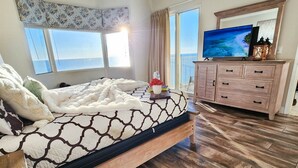 Ein Schlafzimmer mit Bett, Deckenventilator, Fernseher, Kommode und Meerblick.