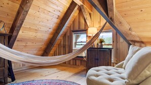 A cozy attic bedroom with a hammock, a plush sofa, and a patterned rug. - Luxury Log Cabin: Scenic Views Near Linville Falls (Marion)
