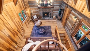 A cozy log cabin interior with a fireplace, leather seating, and a chandelier. - Luxury Log Cabin: Scenic Views Near Linville Falls (Marion)