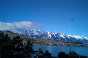 A lake with mountains in the background, a parking area with cars, and a clear sky. - Colonial Village Motel (Queenstown)