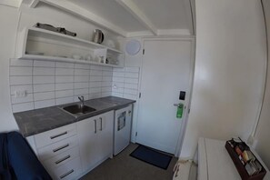 A compact kitchen with white cabinets, a sink, and a small countertop. - Colonial Village Motel (Queenstown)