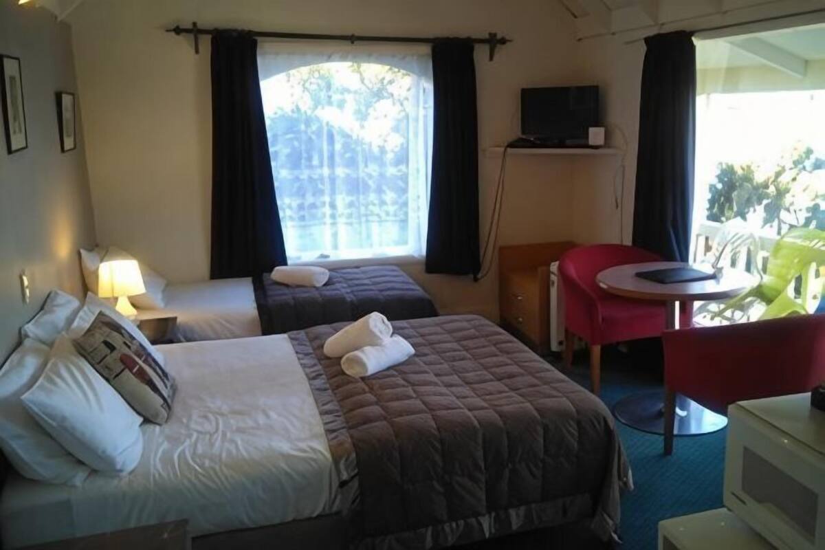 Una habitación de hotel con dos camas, televisión, escritorio y una silla.