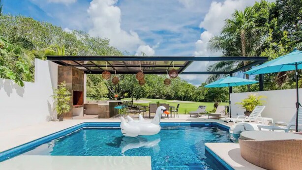 A swimming pool with a swan float, a covered seating area, and lounge chairs. - Spacious villa with 5 bedrooms and WiFi, AC in charming Caribbean community (SOLIDARIDAD)
